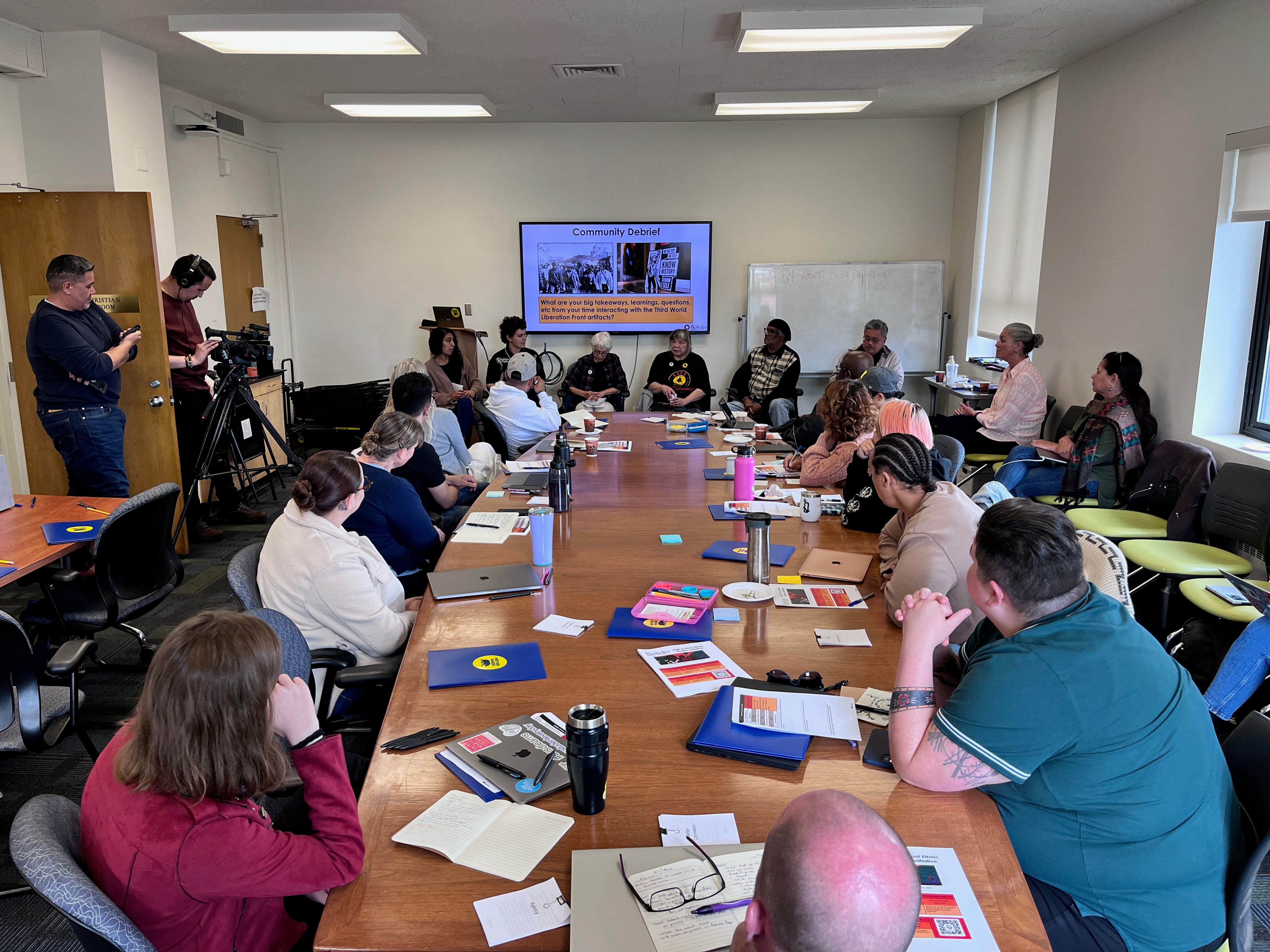 In a boardroom, California teachers listen to Third World Liberation Movement activists, at the front