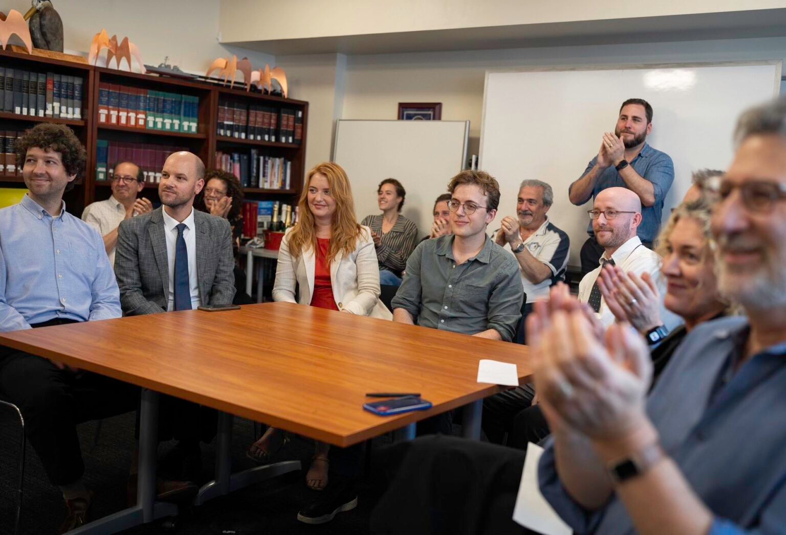 People sit around a table at ProPublica, celebrating winning a Pulitzer