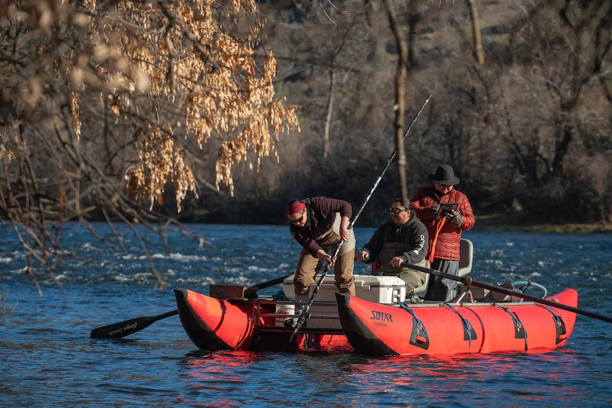 people on a boat on a river collecting fish