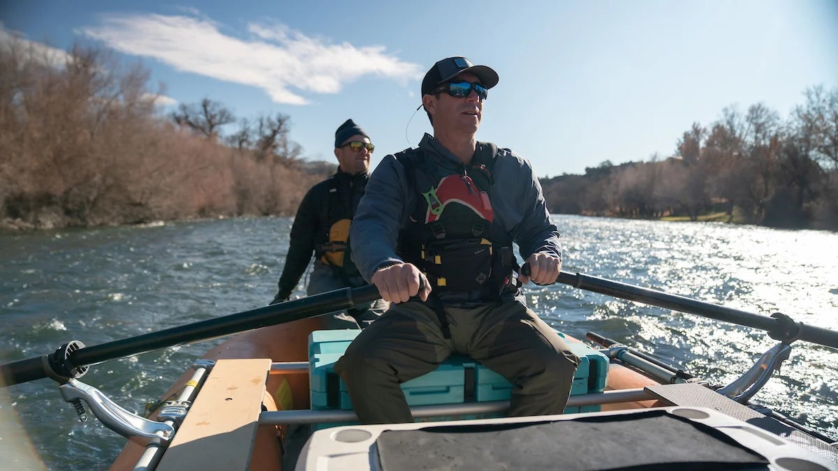 Two people in a boat on a river, one rowing