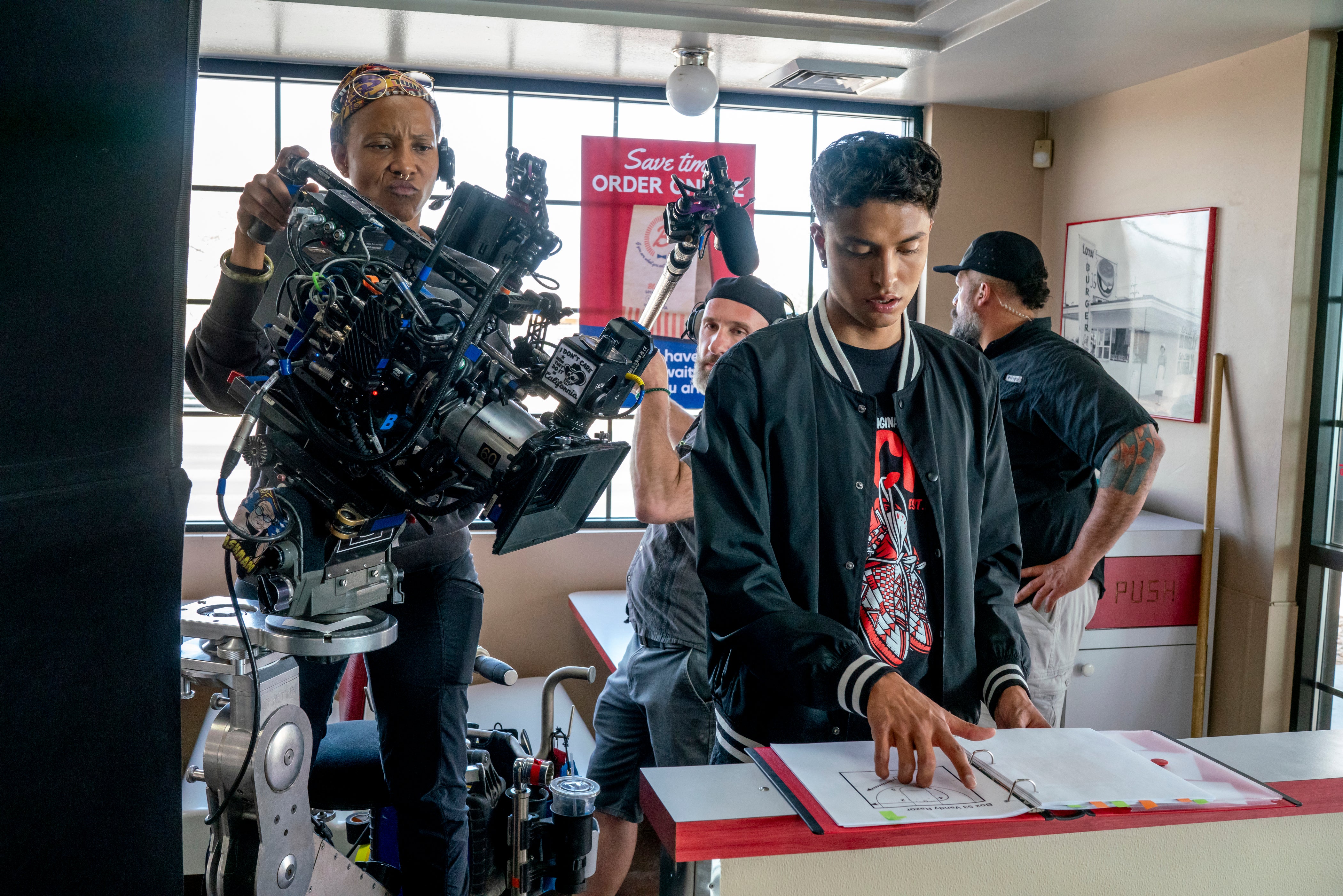 A young man puts his hand on a piece of paper while being filmed with a professional movie camera for Rez Ball