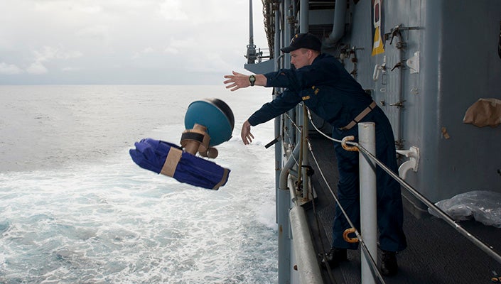 A man throws buoys off the deck of a ship