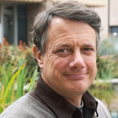 Chris Funk smiles at the camera with a close-lipped expression