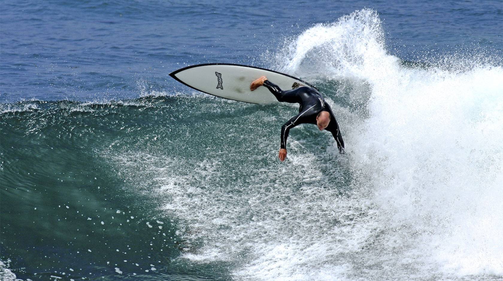 Tyler Callaway in a wetsuit, aggressively surfing a 10-foot wave