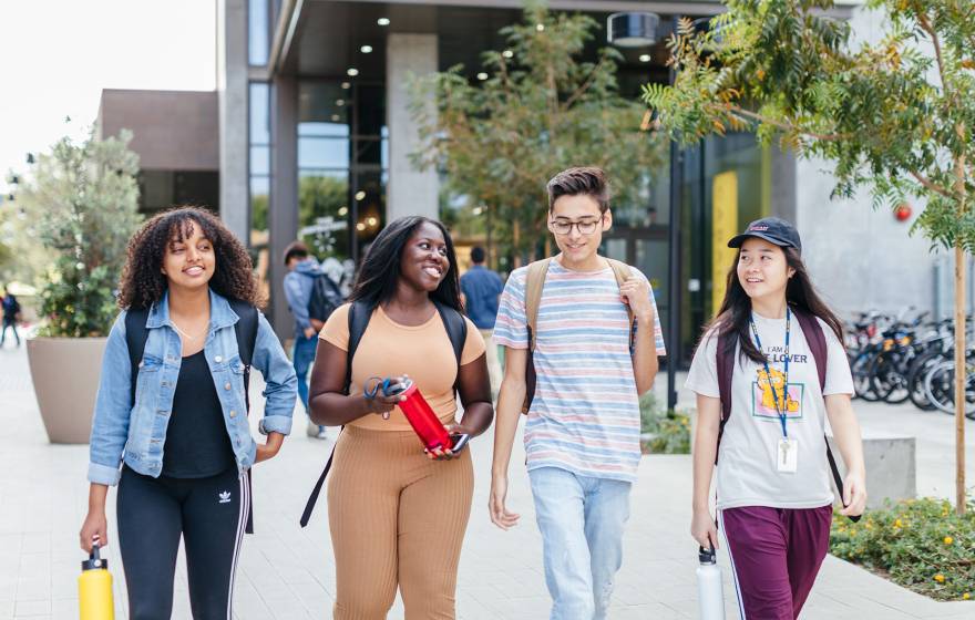 Group of four students walking on campus