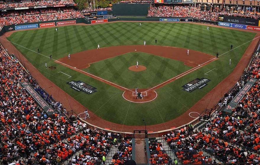A view of a baseball stadium from behind home plate and many rows up