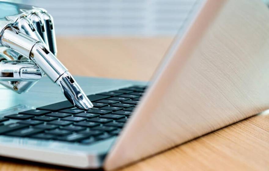 A robot hand presses a keyboard