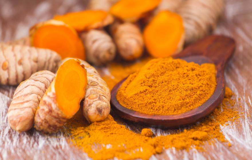 Turmeric root next to turmeric powder