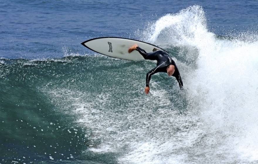Tyler Callaway in a wetsuit, aggressively surfing a 10-foot wave