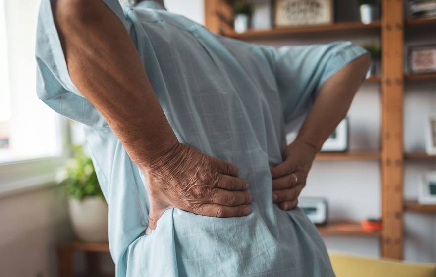 A person holds lower back as if to massage stiffness